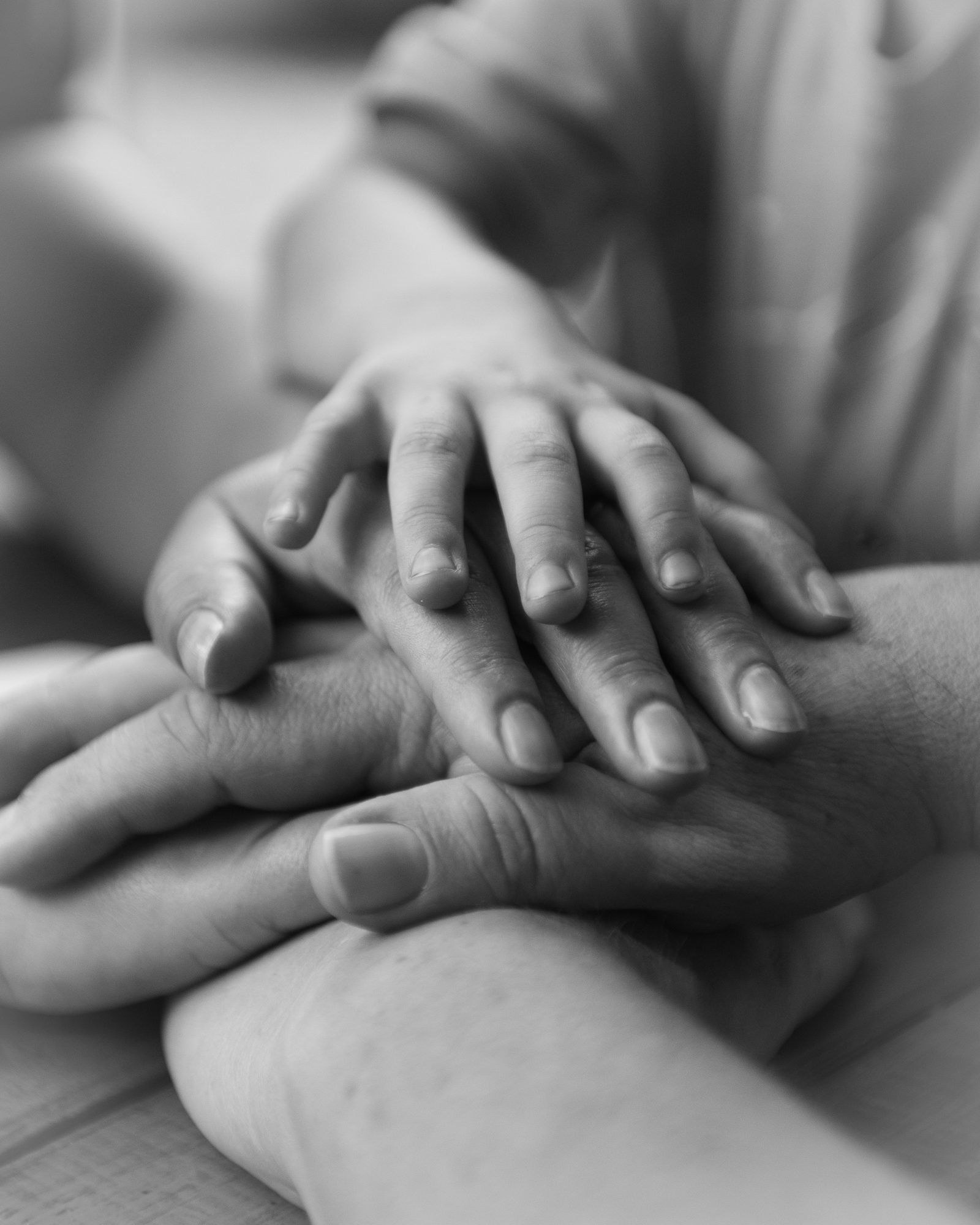 Mehrere Hände liegen übereinander, obenauf eine kleine Hand.