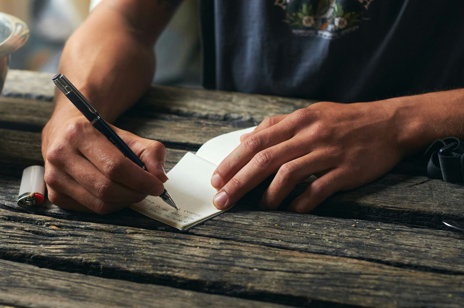 Eine Hand schreibt auf einem Blatt an einem Holztisch